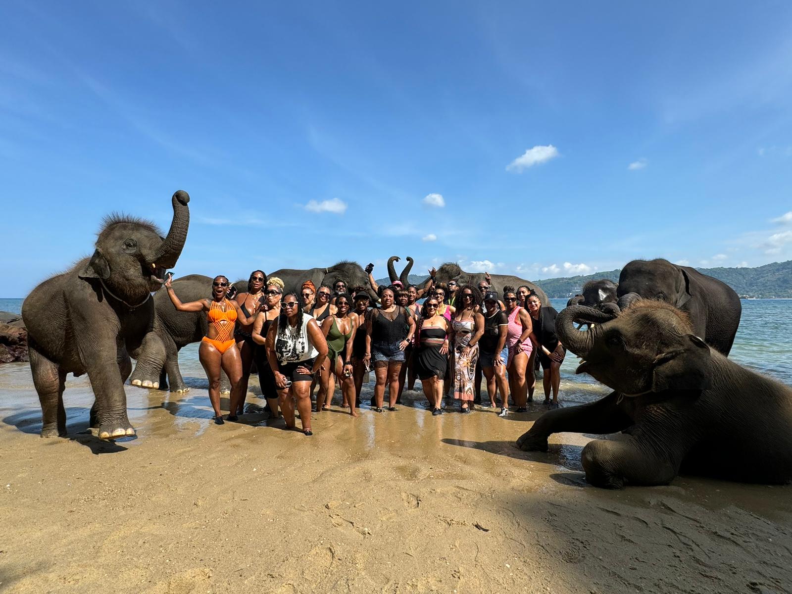 A group of travelers sharing a beach experience with elephants